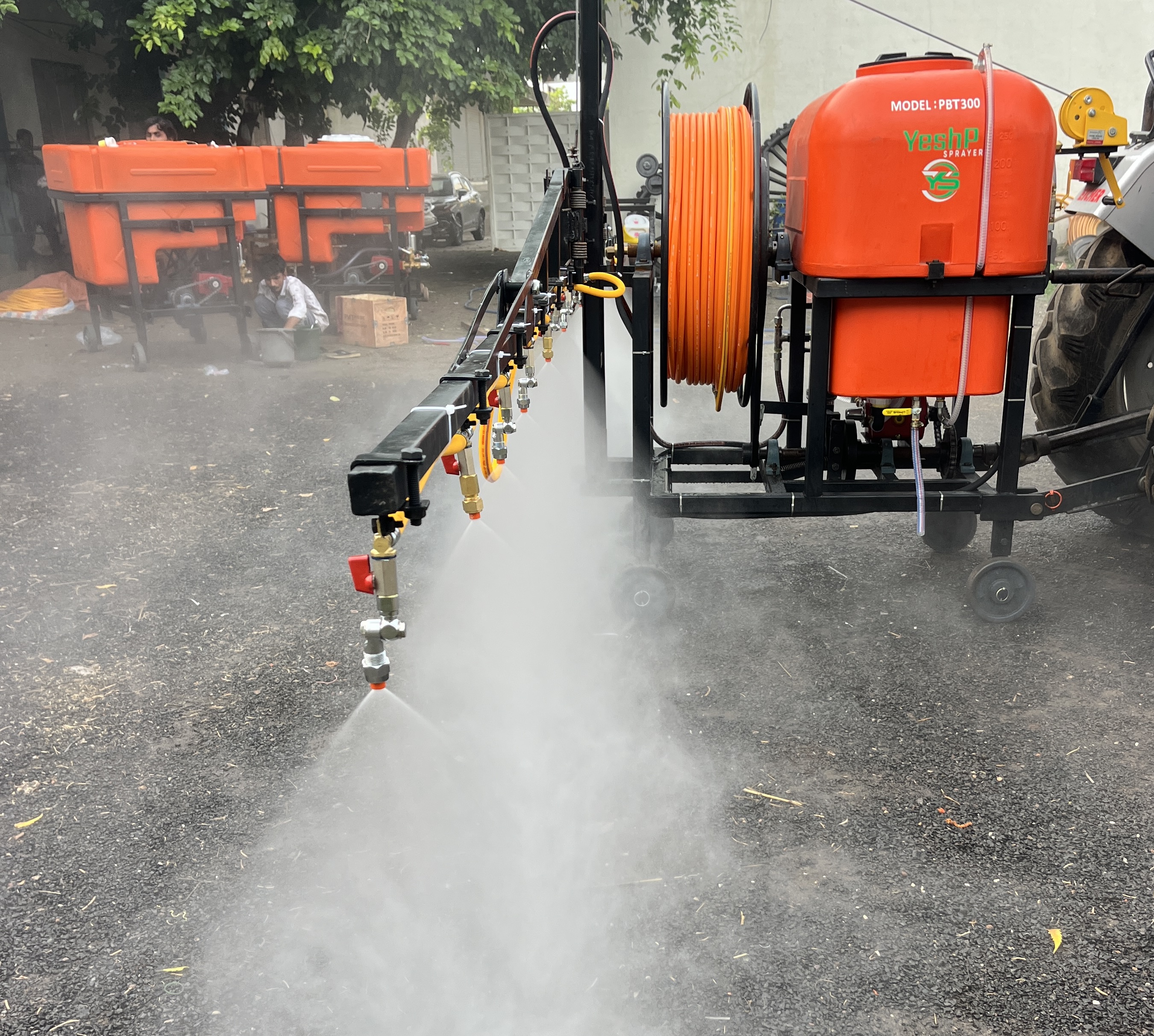 YeshP Sprayer boom spraying a fine mist beside a tractor